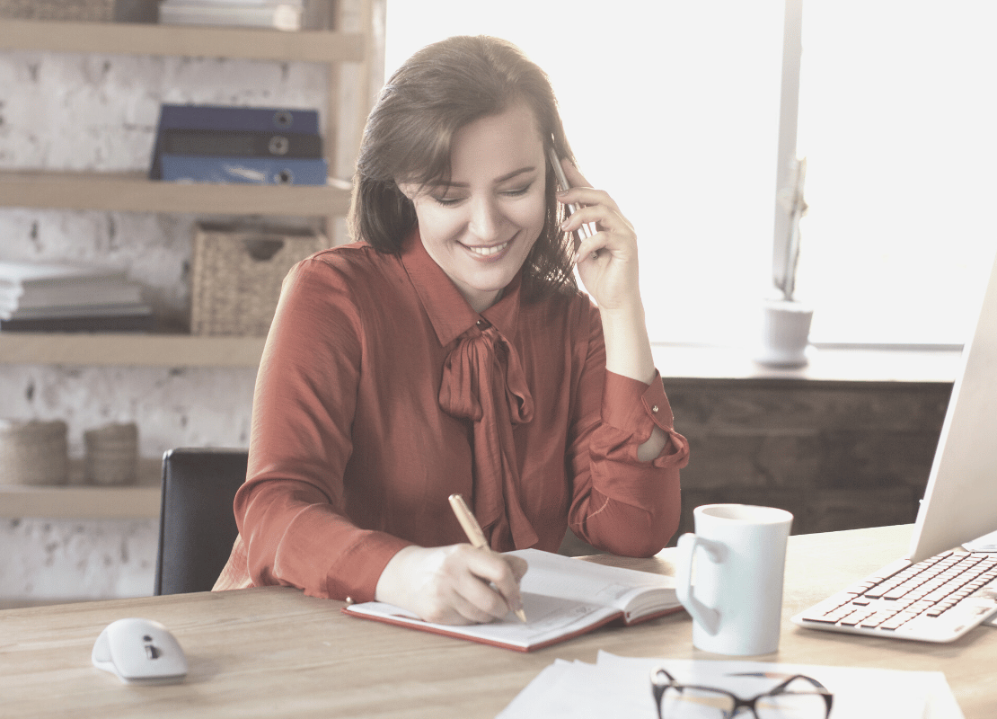 Woman at work on her phone and writing